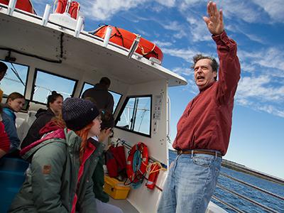 A professor on board a research vessel speaks to students 