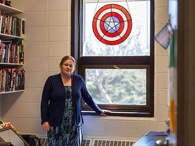 Associate Professor of 政治科学 Annika Hagley stands in her office under a Captain America stained-glass shield.